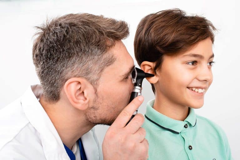 Pediatric-Hearing-Loss-exam An audiologist looks inside the inner ear of a pediatric patient using a medical tool.